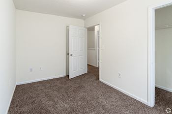 an empty bedroom with carpet and a door to a closet